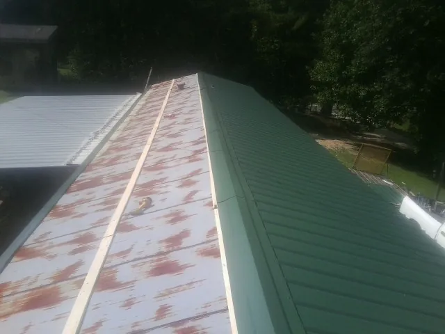 Old rusted panels beside newly installed green metal roofing — Wind Damage Roof Repair by Roofing Brothers in Schellsburg