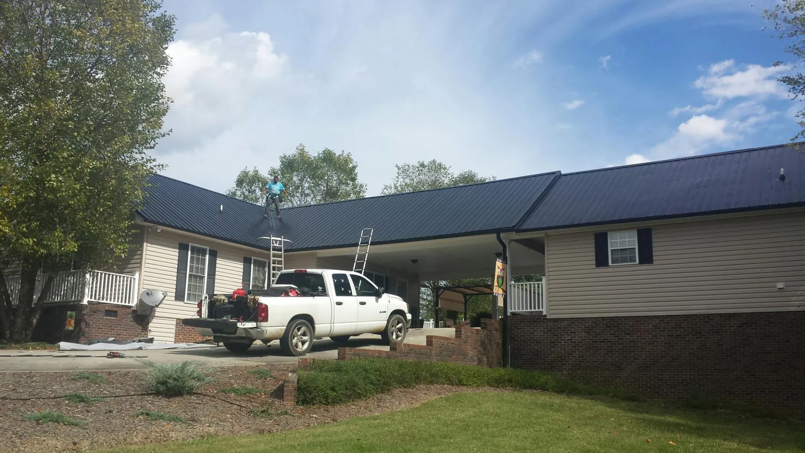 Black metal roof over a home and attached breezeway with ladders set in Schellsburg