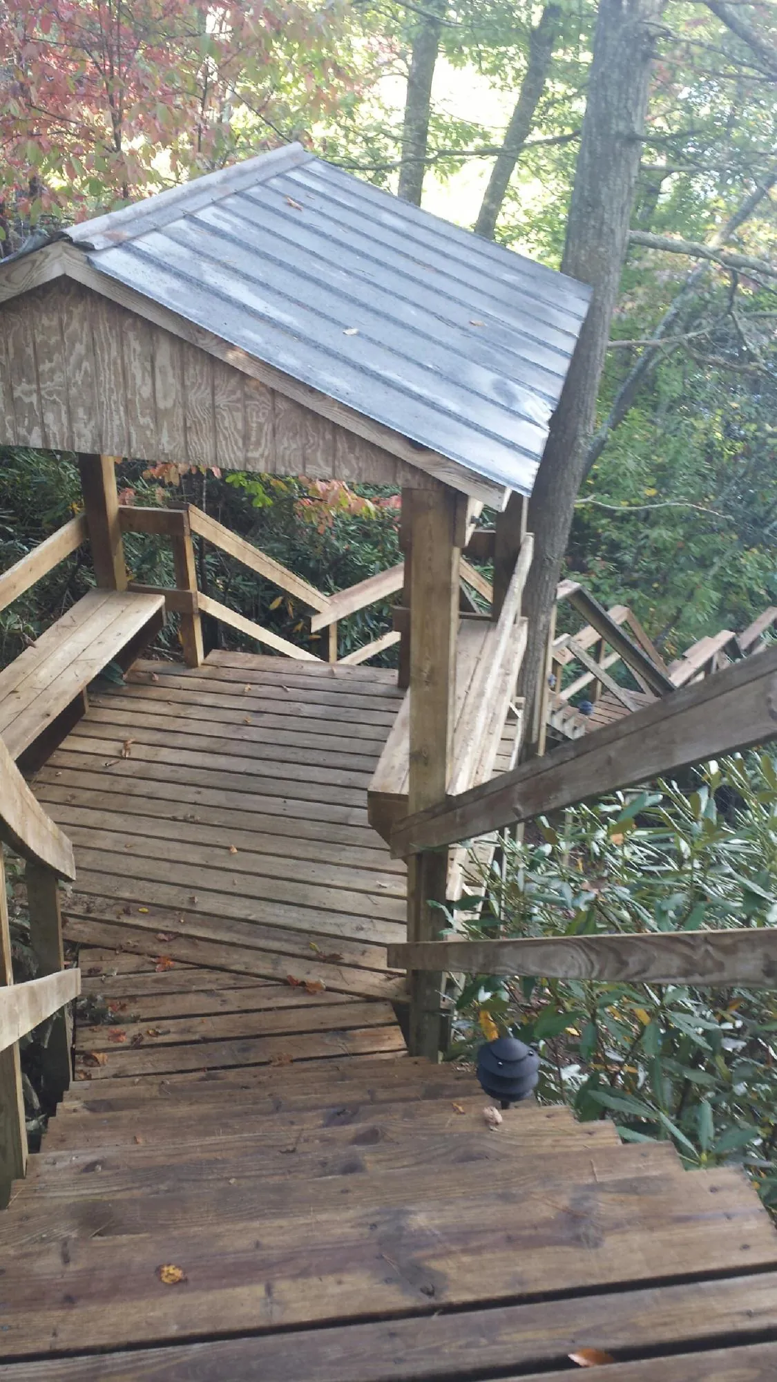 Metal roofed shelter over wooden steps on a wooded walkway — Skylight Repair & Installation work by our crew in Schellsburg