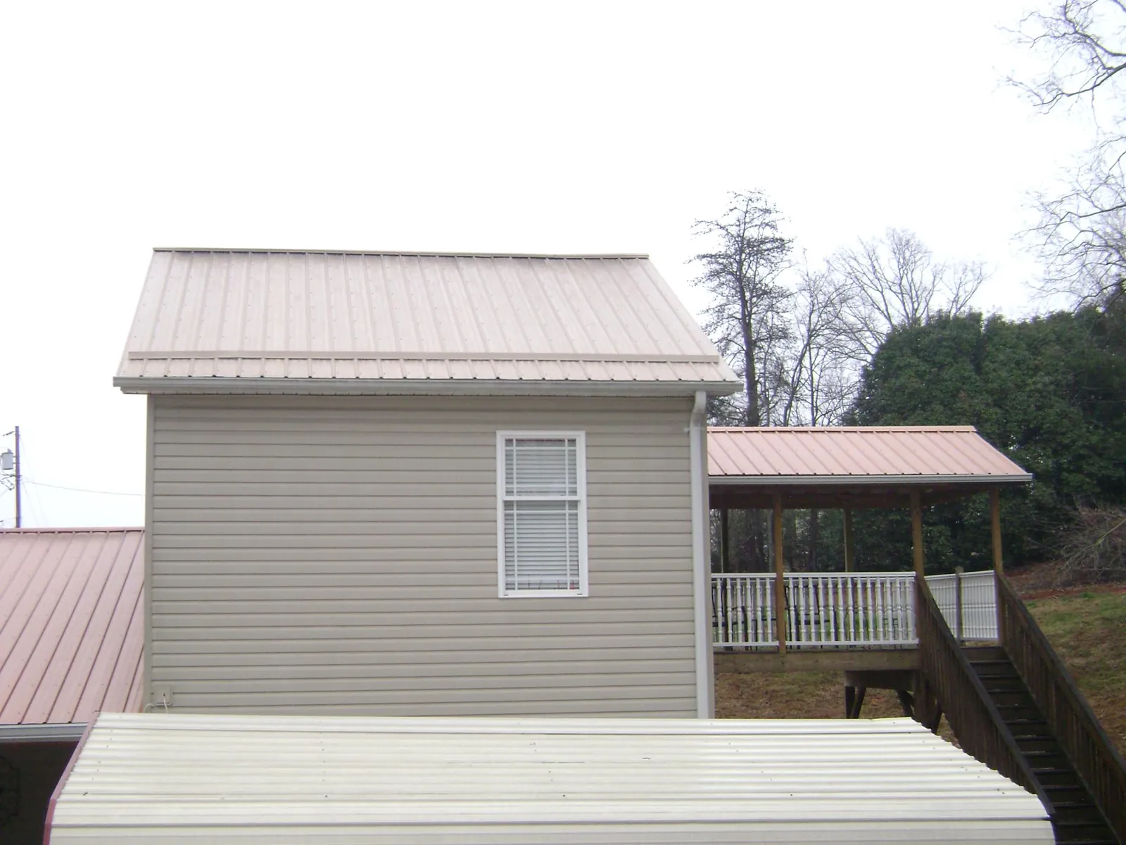 Tan metal roofs on a two story addition and attached porch, from a Roof Replacement job in Schellsburg