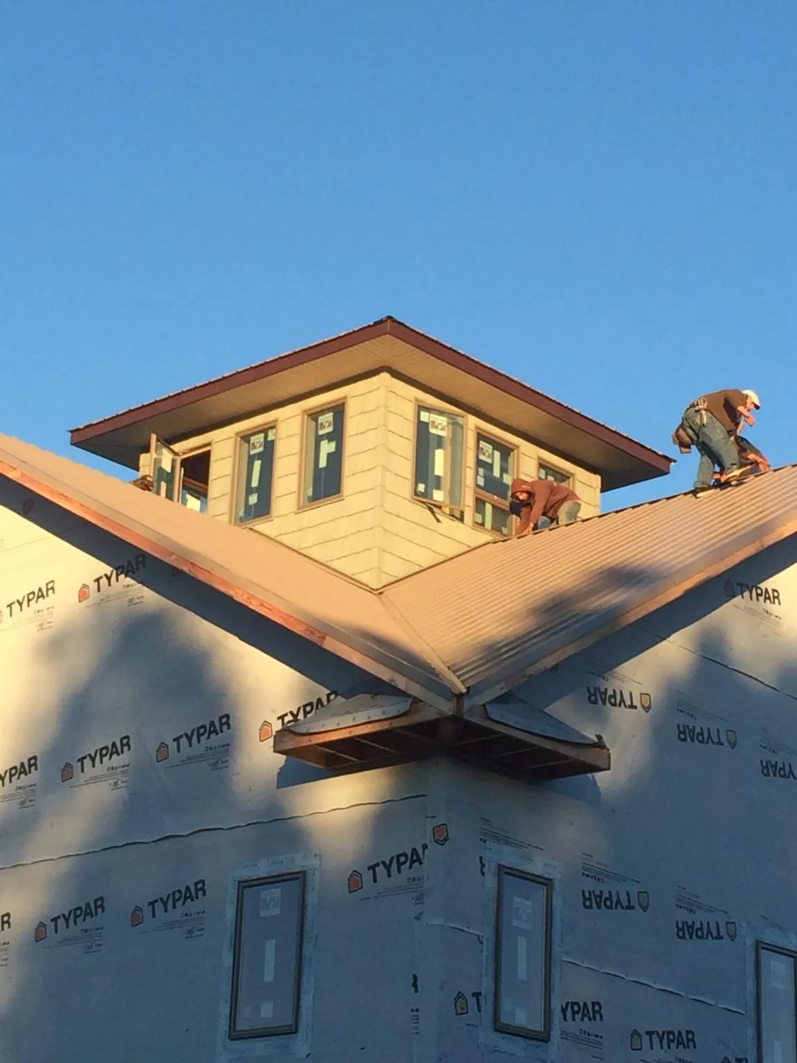 Roofers working around a rooftop cupola on a new metal roof at sunset — Roof Waterproofing in Schellsburg by Roofing Brothers